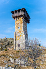 The lookout tower stands tall on Wysoki Kamien, offering stunning views of the Jizera Mountains. It is surrounded by rocky terrain and a tranquil landscape, ideal for hiking and relaxation.