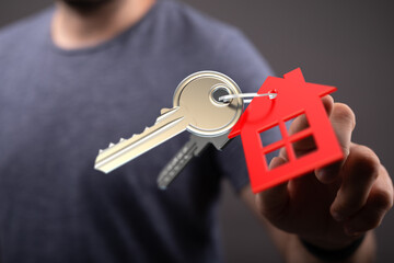 Close up of a hand holding keys with a red house tag, representing new home ownership, real estate...
