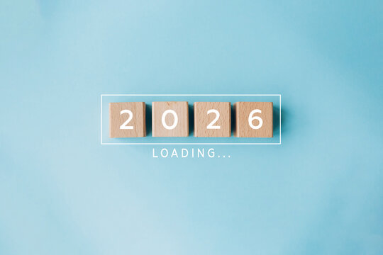 2026 loading concept with wooden cubes on blue background. Concept of new year arrival, anticipation, future plans, and transition from 2025 to 2026.