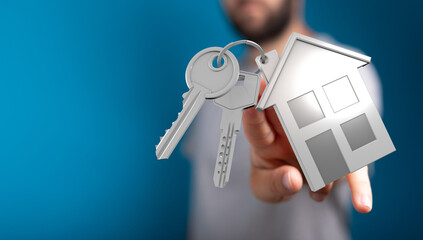 Close-up of a person's hand holding keys and a house model, representing homeownership, real...