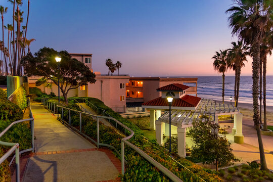Oceanside shoreline with palm trees and sunset at public park.