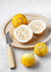 Fresh lemon cucumbers on a ceramic plate, one cut in half showing juicy white flesh and seeds. Natural light still life of organic produce, healthy eating and freshness with rustic kitchen style