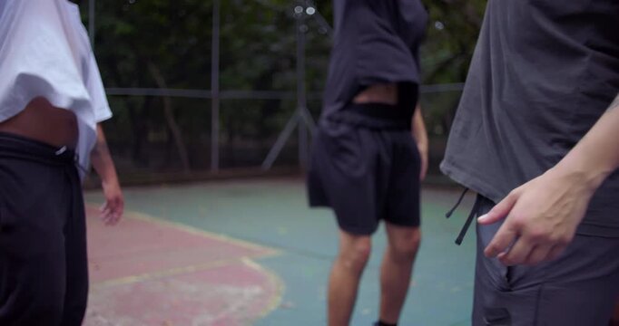 Group of Hispanic and African descent men joining hands over basketball in pregame ritual, teamwork and motivation before match on outdoor court