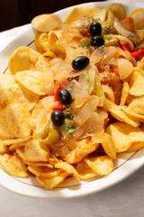 The "Bacalhau com Cebolada", a traditional Portuguese dish made with fried codfish topped with sautéed onions, peppers, and olives, served with crispy round potato chips.