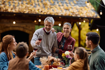 Happy mature man toasting with his family during Thanksgiving celebration on patio.