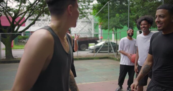 Hispanic and African descent men celebrating score on outdoor basketball court, shouting with joy and energy after intense game, team unity and streetball spirit