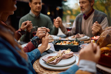 Close up of extended family holding hands while saying grace on Thanksgiving.
