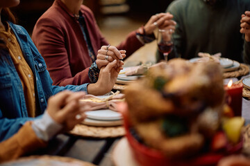 Close up of multigeneration family holding hands while praying at dining table on Thanksgiving.