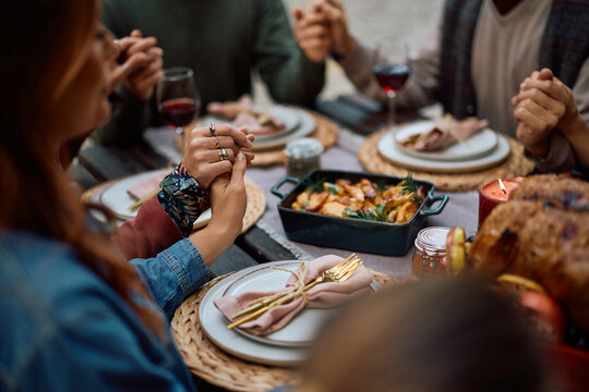 Close up of multi-generation family praying before Thanksgiving dinner at dining table.