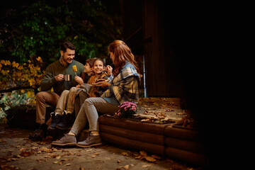 Obraz premium Happy parents and their kids relaxing in backyard in evening in autumn.