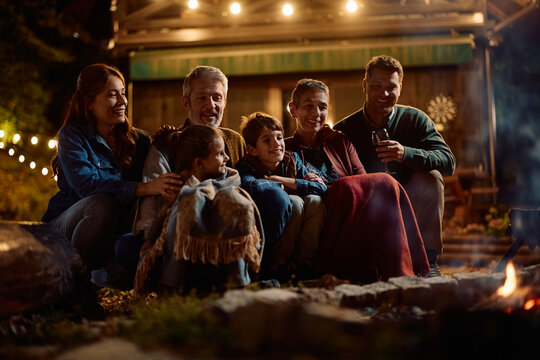 Happy extended family enjoying in cozy autumn evening by campfire.