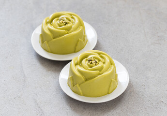 Pistachio cream dessert in the shape of a rose. Decorated with chopped pistachios.