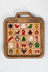 Advent Calendar. 25 festive square cookies with colored curly marmalade filling. On a wooden plate. White background. Top view