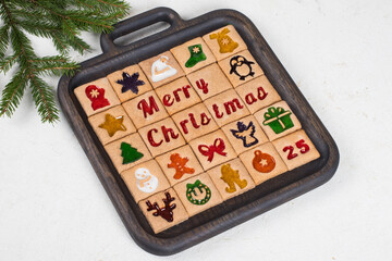 Advent Calendar. 25 festive square cookies with colored curly marmalade filling. On a wooden plate. White background. Close up