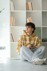 young man with mobile phone at home in casual outfit
