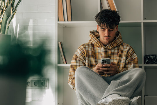 teenager at home with cell phone sitting on the floor