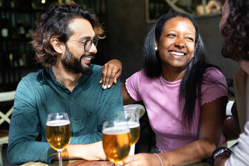 Multi-ethnic friends enjoying drinks and conversation at a bar, sharing laughter and good times together