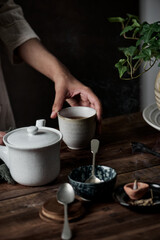 Woman holding cup of hot Tea on rustic wooden table, closeup photo, winter morning concept
