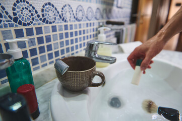 Morning Bathroom Routine With Mug, Soap Dispenser, And Hand At The Sink