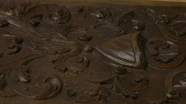 Intricate wooden carving detail showcases craftsmanship, camera zooms in to reveal texture and design elements. Woodworking restoration concept 