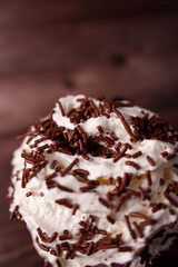 close-up of swirled whipped cream with chocolate sprinkles on textured wooden background, capturing a tempting and sweet culinary delight with soft focus and warm lighting, luxury, contrast, warm