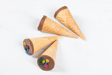 Turkish Waffle dessert. Waffle cones with chocolate nut cream and colored dragees on top.  Close up. White background	