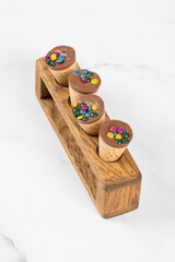 Turkish Waffle dessert. Waffle cones with chocolate nut cream and colored dragees on top. On a wooden stand. Close up. White background	