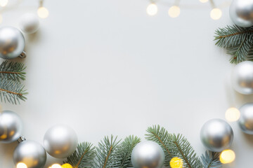 Christmas background with silver ornaments fir branches and string lights festive holiday frame for seasonal greetings and invita