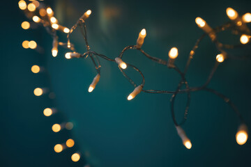 String of warm white fairy lights festive decoration for holiday season against a dark teal background