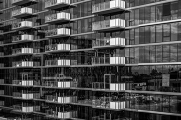 Black Glass Building with White Balconies and Clouds Reflected in Windows.