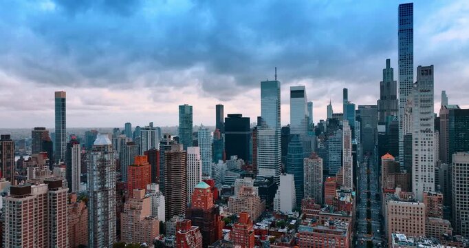 Flight above the dense cityscape of Manhattan, New York, USA. Gorgeous skyscrapers of big Apple against cloudy sky.