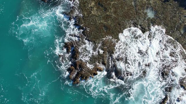 shoreline off Hawaii with a drone shot of waves on rocks
