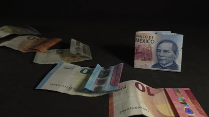 The domino effect with falling euro banknotes revealing a Mexican peso bill in slow motion