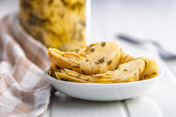 Pickled artichoke in bowl on white table.