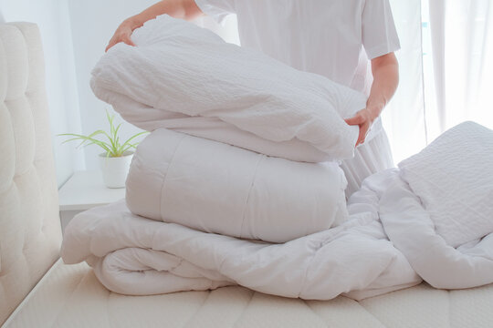 Woman changing bedding with duvets and pillows on bed in bedroom, seasonal home care, bedding washing, cleaning and care