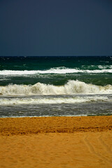 wzburzone morze z falami, plaża nad morzem, żółty piasek na plaży na tle wzburzonego morza, spienione morskie fale, foaming sea waves, yellow sand on the beach against the background of a stormy sea	
