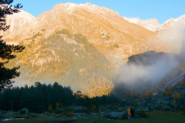 Two girls admire a mountain sunset through enveloping fog, sharing a moment of awe in nature's grandeur.