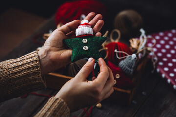 Young woman holding wooden box with artisan handmade Christmas toys. Simple DIY decorations for fir tree, holiday creative design. Leisure time with kids, art and craft. Recycled or natural materials