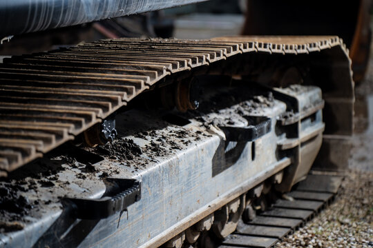 Detailed excavator steel crawler track with visible rollers and mud deposits showing advanced traction engineering, load distribution, and industrial durability in construction machinery