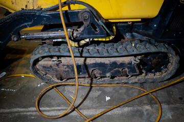 Tracked undercarriage of compact excavator with hydraulic lines and rubber track showing mechanical...