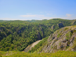 Fototapeta premium Magnificent mountainous landscape with lush greenery, river, and clear blue skies. nature's perfect harmony and the breathtaking serenity of untouched wilderness landscapes.