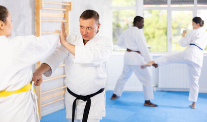 Obraz premium Multinational partners during martial arts karate class train to perform basic blows to opponent with hands and feet. Preparation of athletes for competitions