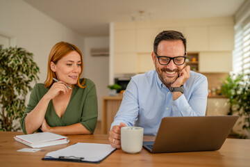 Couple working from home planning finances online using laptop