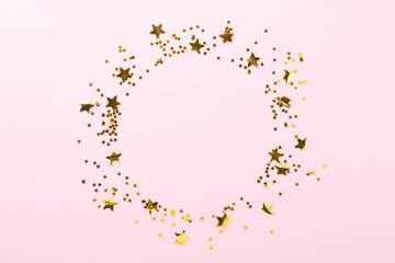 Golden star shape confetti on color background, top view