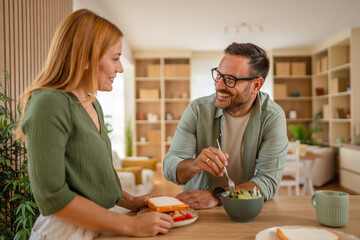 Smiling couple preparing healthy salad in modern kitchen