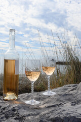 Close-up of a glass of rosé wine. Engraved crystal glass. Tall grasses and the Mediterranean Sea in the background. In the Camargue.