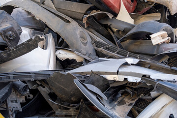 Old and damaged car bumpers collected for recycling. Discarded vehicle bumpers stacked in a...