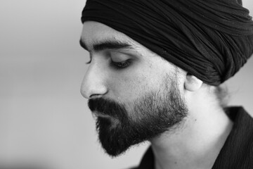 Close up of a bearded man wearing a turban with his eyes closed in contemplation and reflection with a thought provoking expression