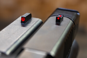 Detailed comparison macro photo of two modern pistol front sights, featuring bright red high-visibility fiber optic inserts for aiming.