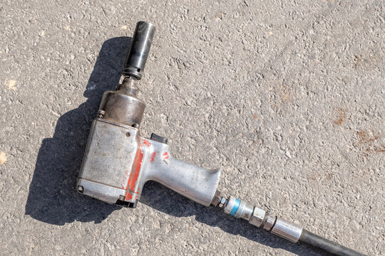 Pneumatic impact wrench on stone floor. Heavy duty pneumatic tool on stone ground. Industrial pneumatic wrench on workshop floor.